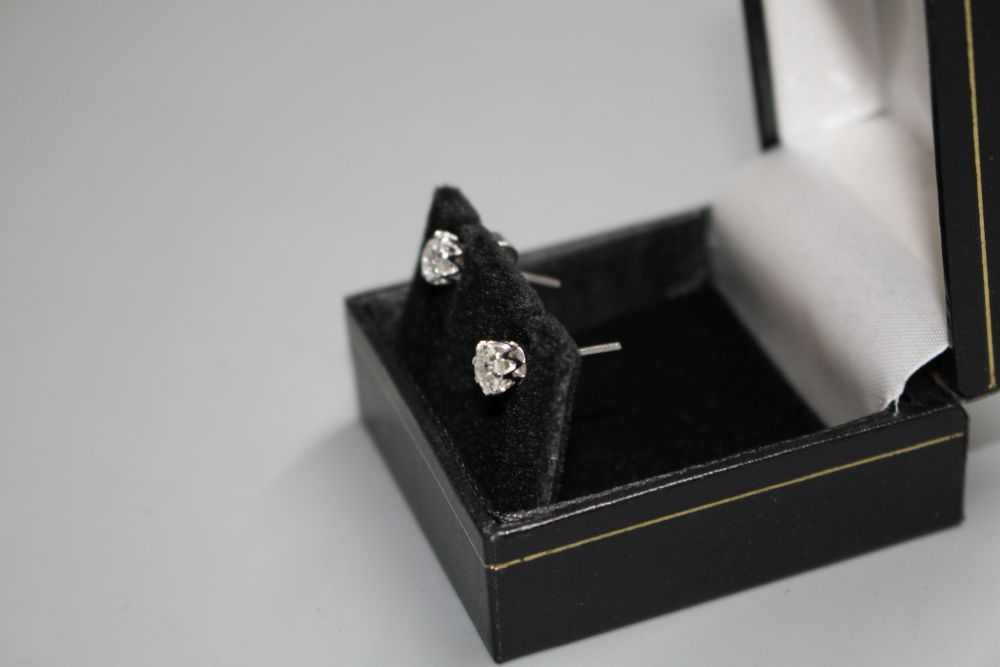 A pair of white metal and solitaire diamond ear studs,